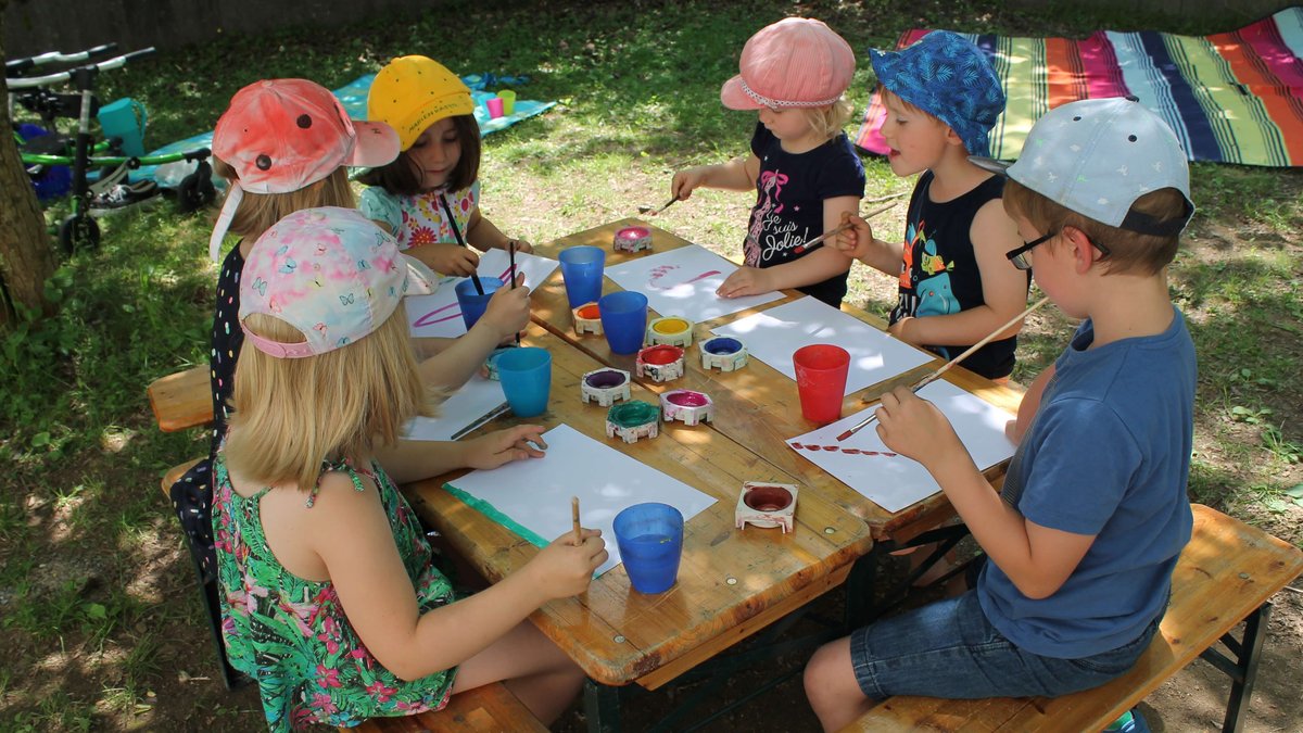 Das Bild zeigt Kinder in der Gruppe beim Malen im Garten